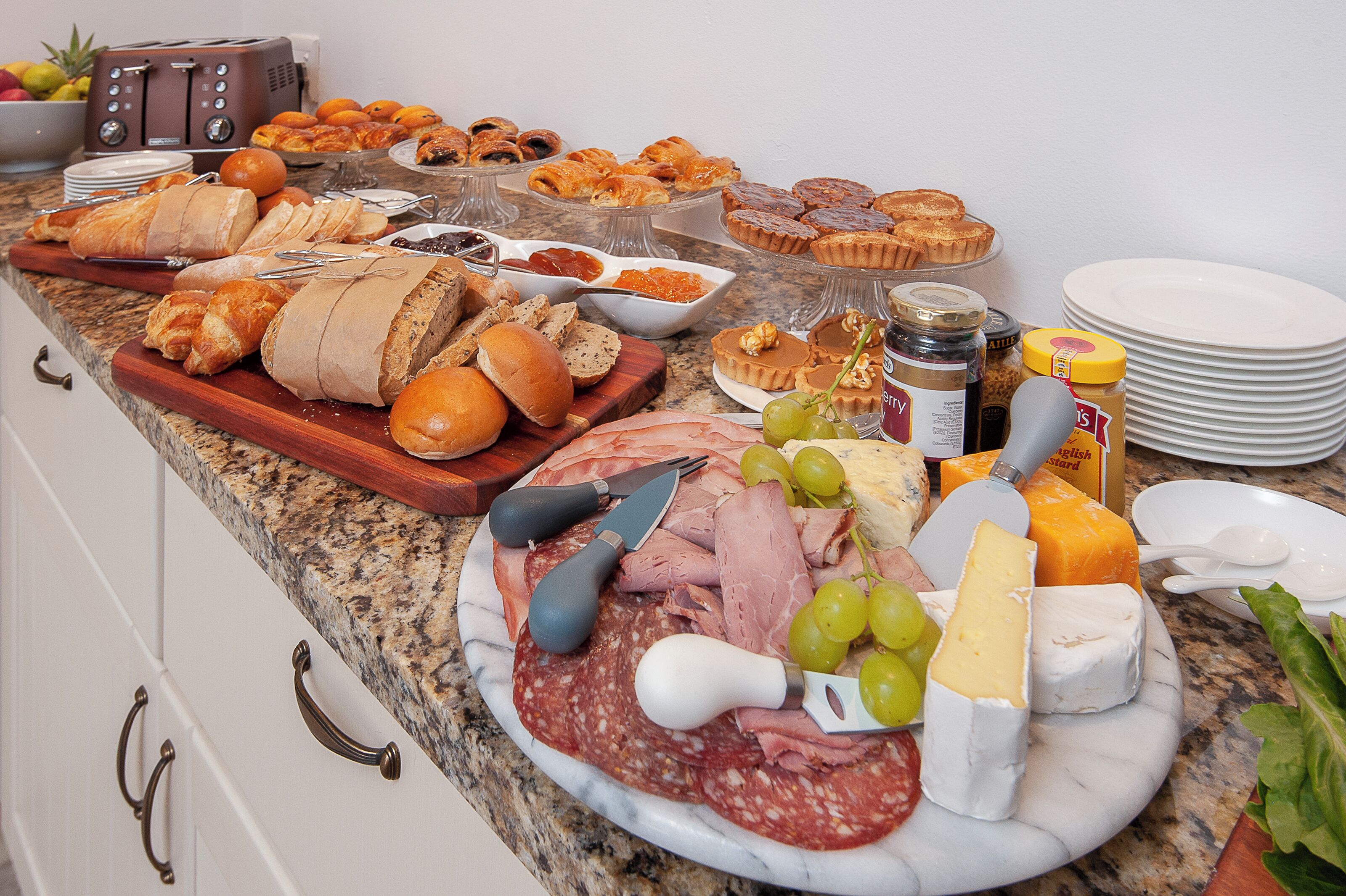 A buffet with various food items including bread, pastries, cheese, and meats.