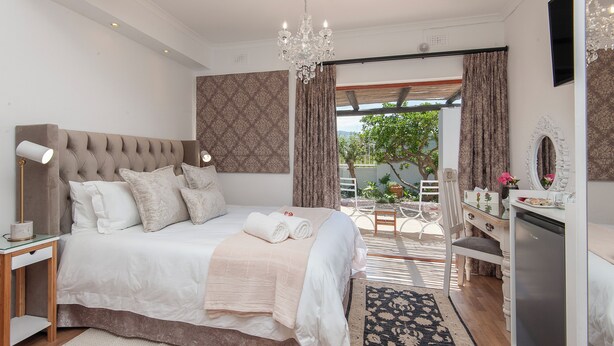 A modern bedroom with a large bed, bedside table, and a dresser. - Villa Venusta (Hermanus)