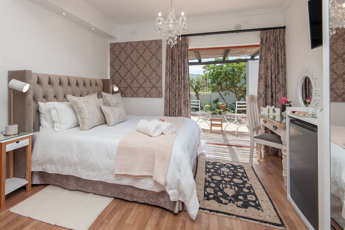 A modern bedroom with a large bed, bedside table, and a dresser.