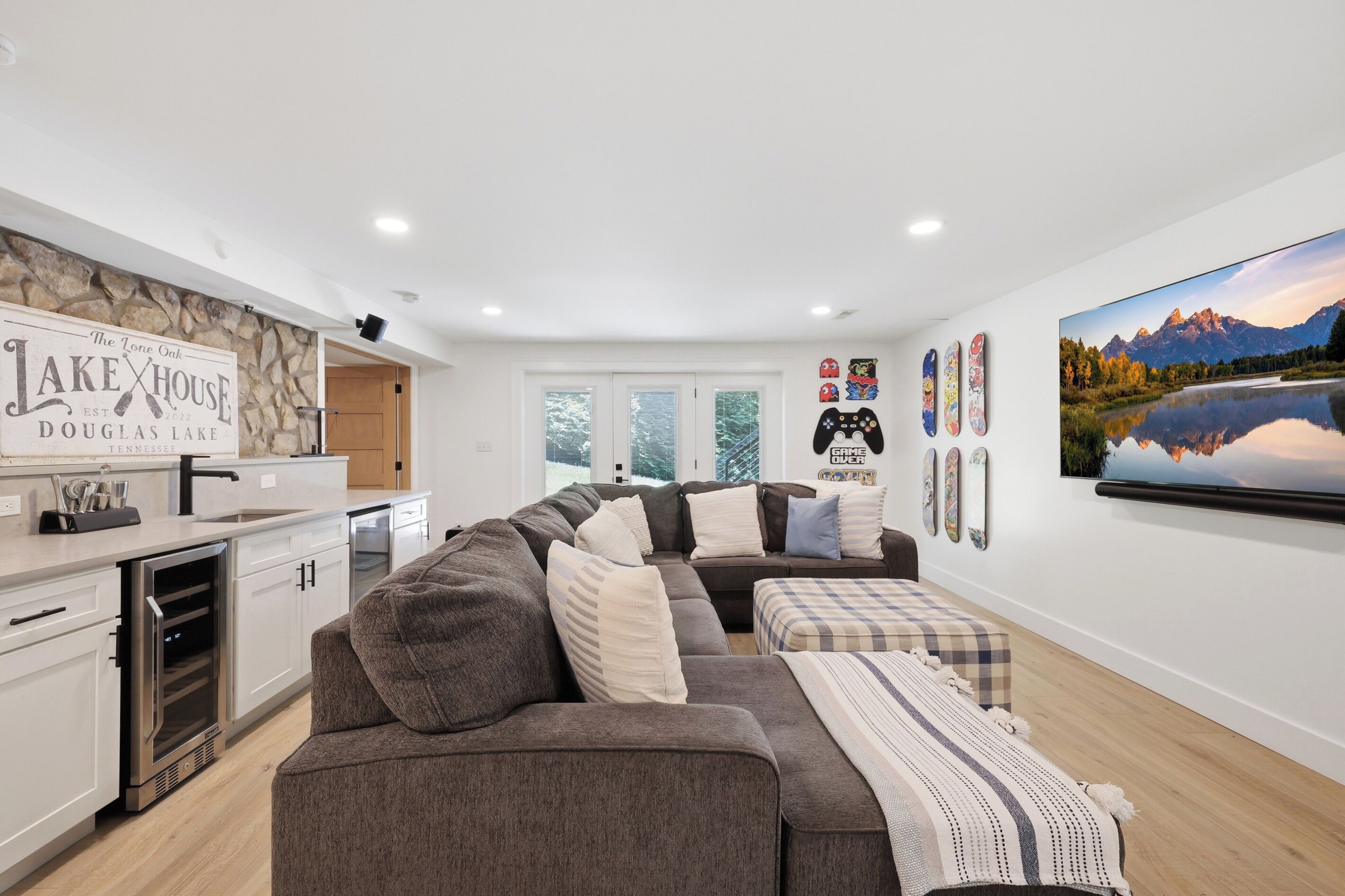 A modern living room with a sofa, a dining area, a kitchen with a built-in oven, and a large window.