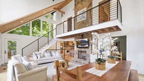 Un amplio espacio habitable con una mesa de comedor de madera, un sofá y una chimenea.