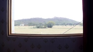 Janela com vista para um campo e uma montanha.
