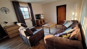 Una sala de estar con un sofá, una mesa de centro, un televisor y un mueble.