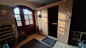 Un interior rústico de madera con una bodega, una puerta con escudo heráldico y una pequeña mesa de madera.