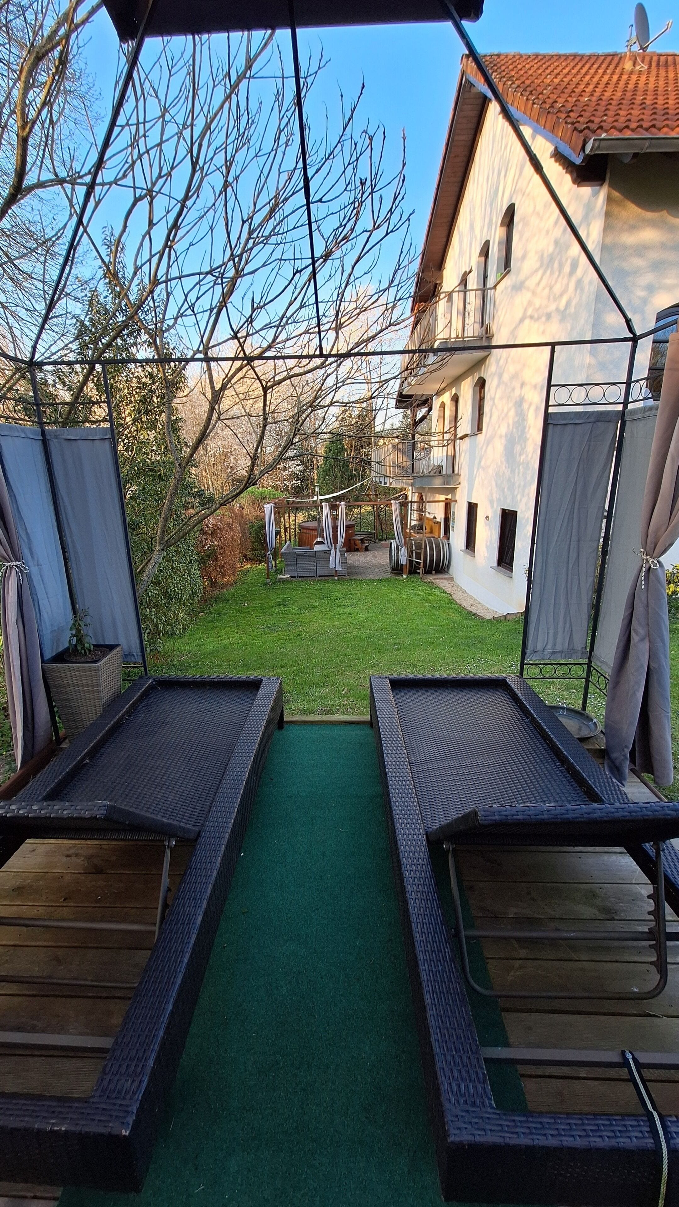 A patio area with two lounge chairs, a small table, and a covered seating area.