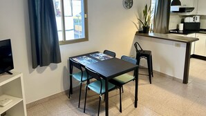 Ein kompakter Wohnbereich mit Essbereich, Küchenzeile und Fernseher auf einem Regal.