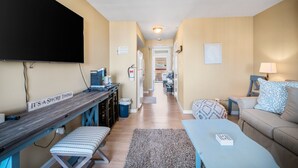 A living room with a TV, a desk, a couch, and a rug.