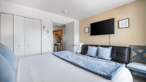 A modern hotel room with a large bed, a flat-screen TV mounted on the wall, and a wardrobe with sliding doors.