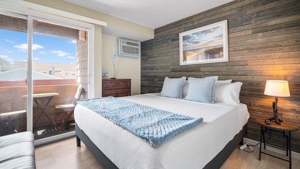 A bedroom with a large bed, a wooden wall, a window, and a view of the outside.