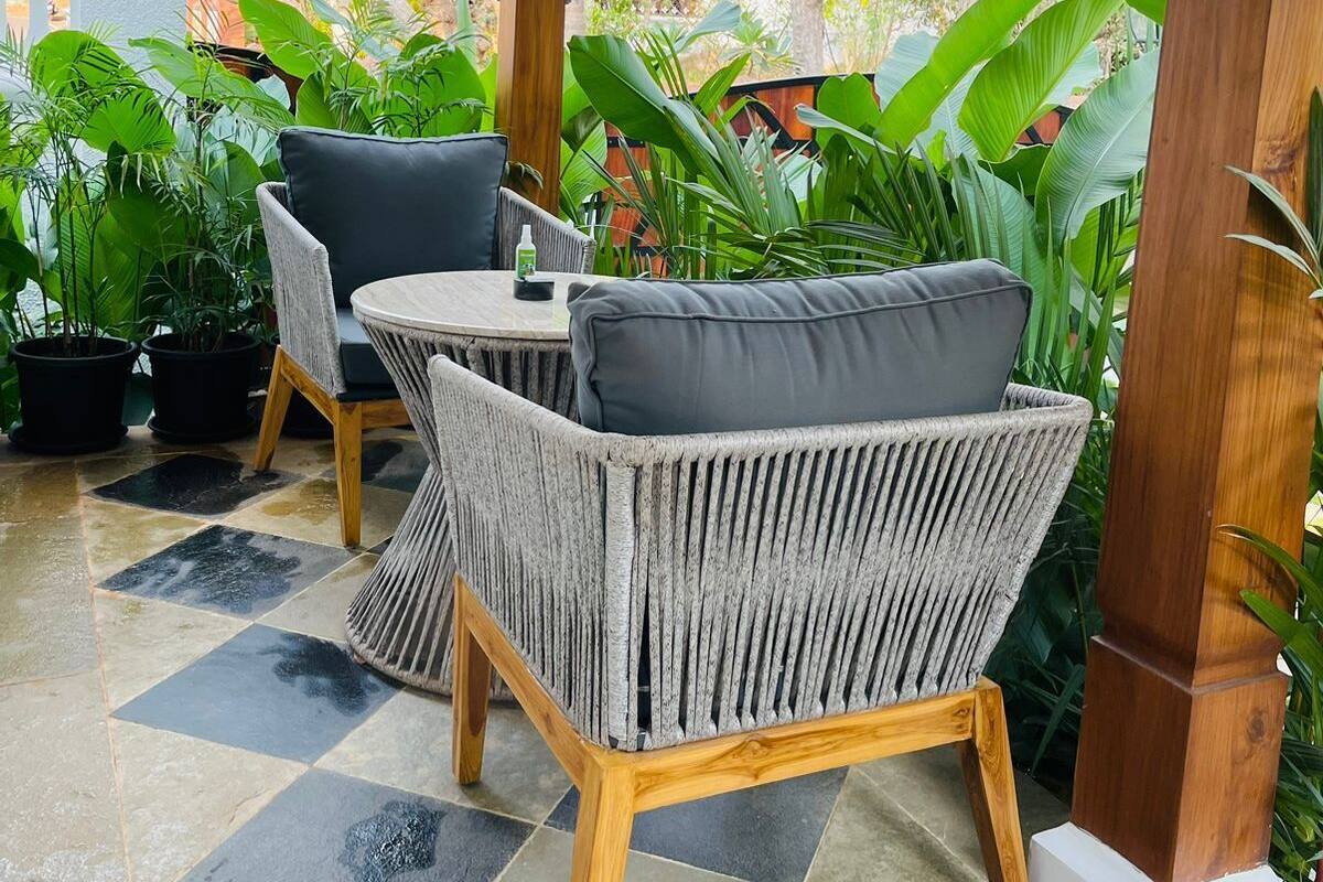 A covered outdoor seating area with wicker furniture and a tiled floor.