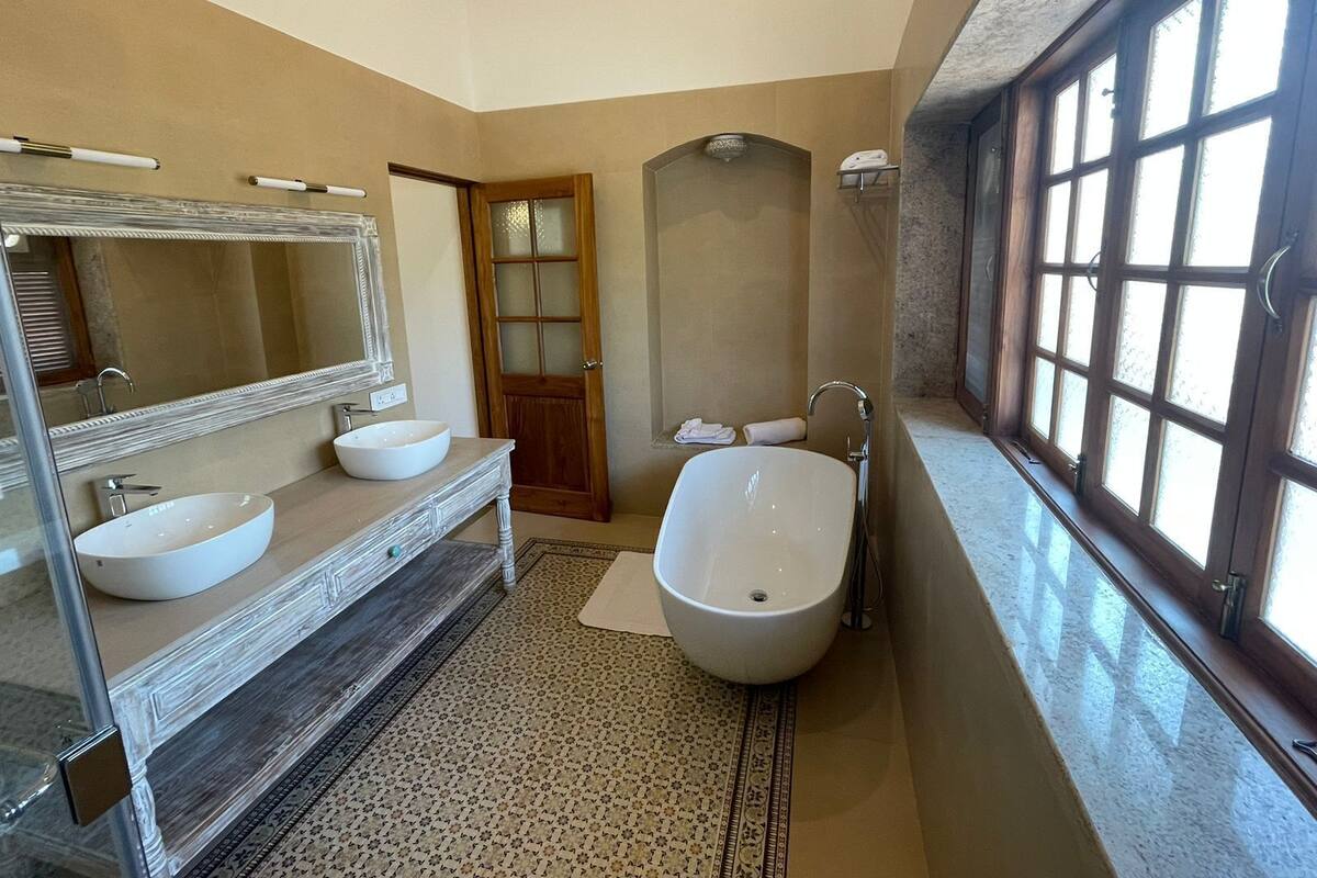 A bathroom with two sinks, a large bathtub, a mirror, and a window.