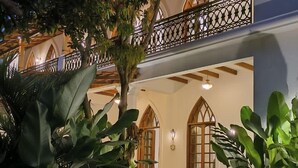 A multi-level building with a balcony, stone pathway, and lush greenery. - The Postcard Saligao (Consua)