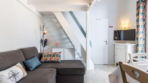 Un salon moderne avec un canapé, un téléviseur et un escalier.