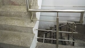 A staircase with metal railings and a white wall. - Roomshala 034 Grihum Noida Sector 63 (Noida)
