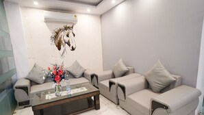 A modern living room with a sofa set, a coffee table with a vase of flowers, and a wall-mounted air conditioner. - Roomshala 034 Grihum Noida Sector 63 (Noida)
