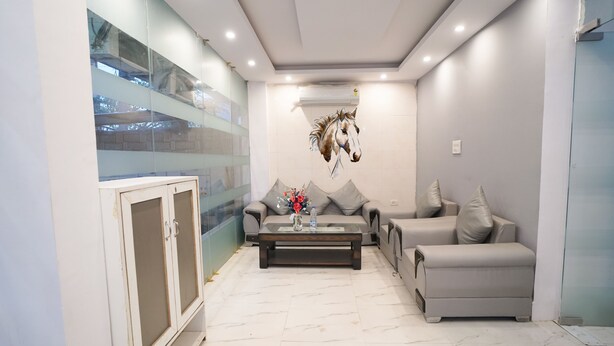 A modern living room with a glass wall, a sofa set, a coffee table, and a decorative horse mural. - Roomshala 034 Grihum Noida Sector 63 (Noida)