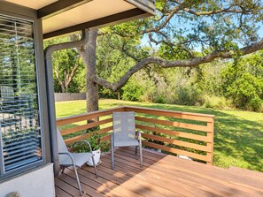 A wooden deck with two chairs and a table, overlooking a grassy yard with trees. - Paradise by the River - Relax in Style Near the Beach! Pool and Heated Spa (St. Augustine)