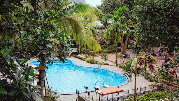 A swimming pool surrounded by lush greenery and outdoor seating areas.