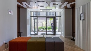 A modern interior with a 'WORK' sign, a glass door entrance, and a seating area with a power outlet. - SA1342 - Apartment 2 Suites Vila Nova Conceição (São Paulo)
