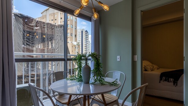 A dining area with a round table, chairs, a vase, and a potted plant. - SA1342 - Apartment 2 Suites Vila Nova Conceição (São Paulo)