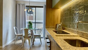 A modern kitchen with a built-in oven, a sink, and a dining area with chairs and a table. - SA1342 - Apartment 2 Suites Vila Nova Conceição (São Paulo)