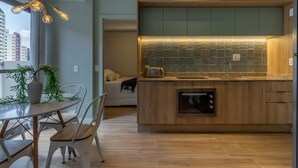 A modern kitchen with wooden cabinets, a built-in oven, and a dining area with a table and chairs. - SA1342 - Apartment 2 Suites Vila Nova Conceição (São Paulo)