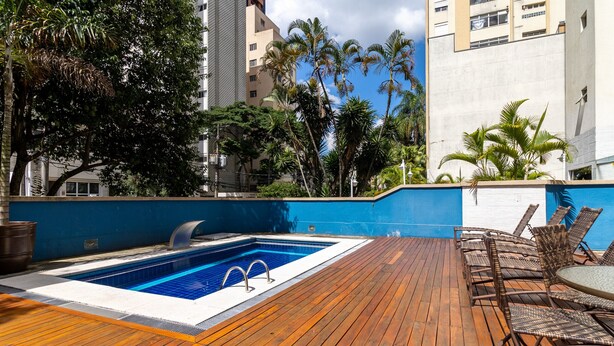 Ein Pool auf dem Dach mit einer Holzterrasse und Korbmöbeln.