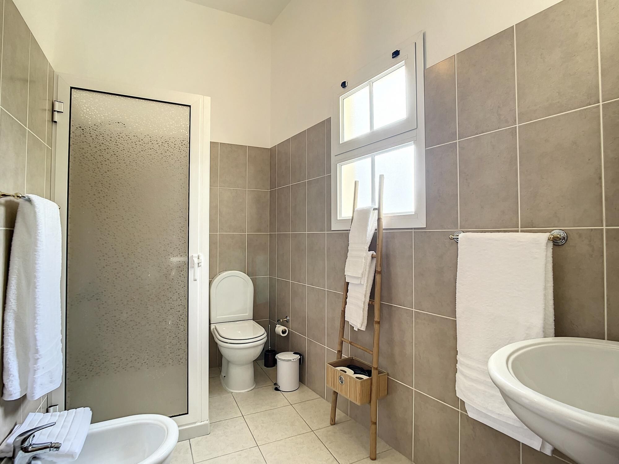 A bathroom with a toilet, a shower, and a sink.