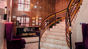 Een luxe hotel receptie met een marmeren trap en een receptiebalie.