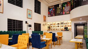 Een restaurant met groen en geel bekleden zitbanken, een bar met flessenrekken en een marmeren vloer.