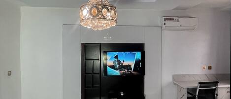 Un salón moderno con un televisor de pantalla plana montado en la pared, una chimenea de mármol y una lámpara en el techo.