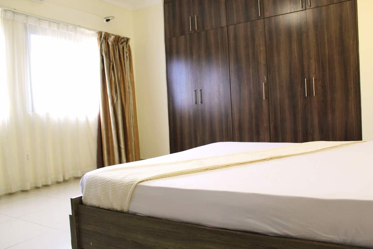 A bedroom with a bed, curtains, and a wardrobe.