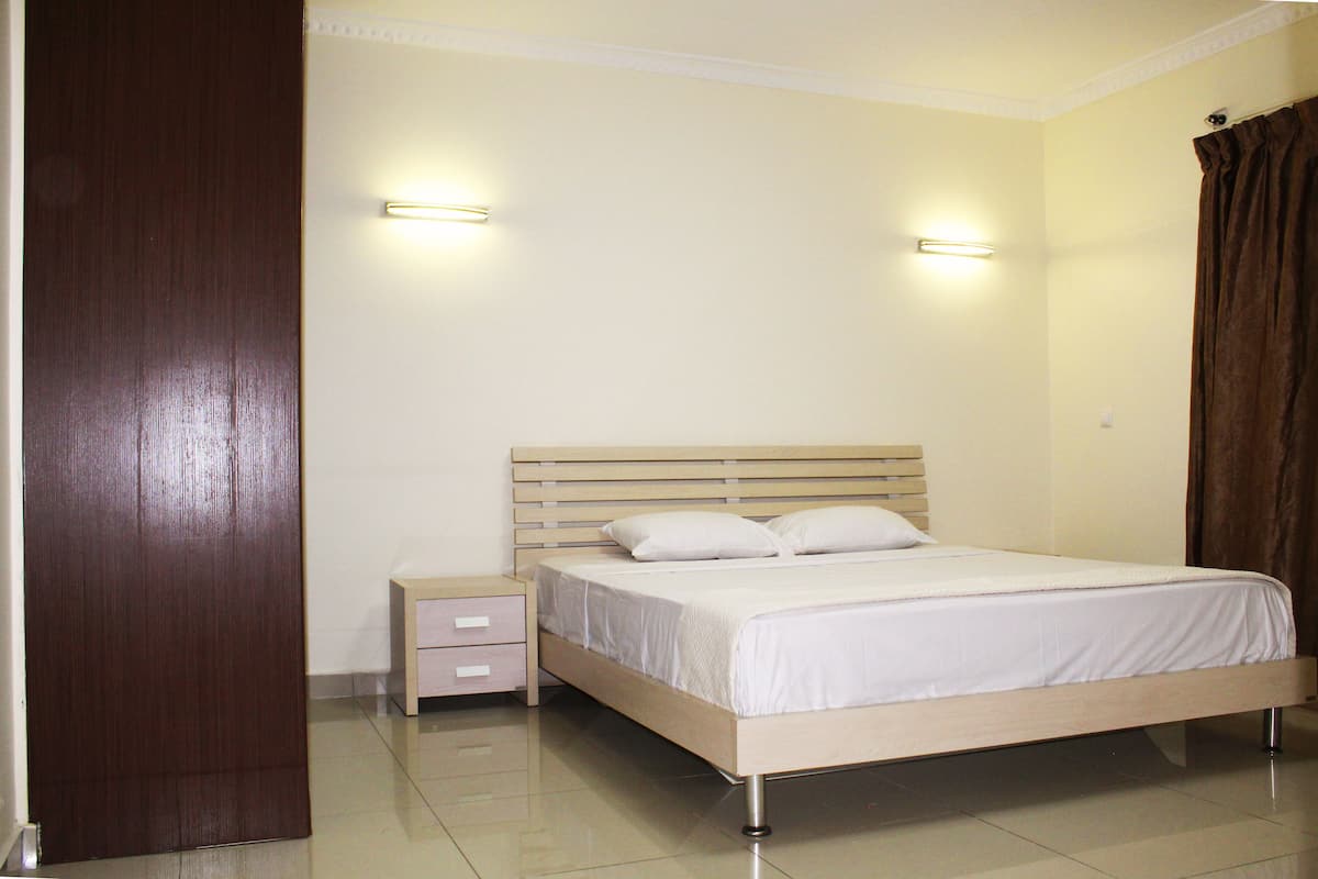 A bedroom with a wooden bed, two bedside tables, and a nightstand.