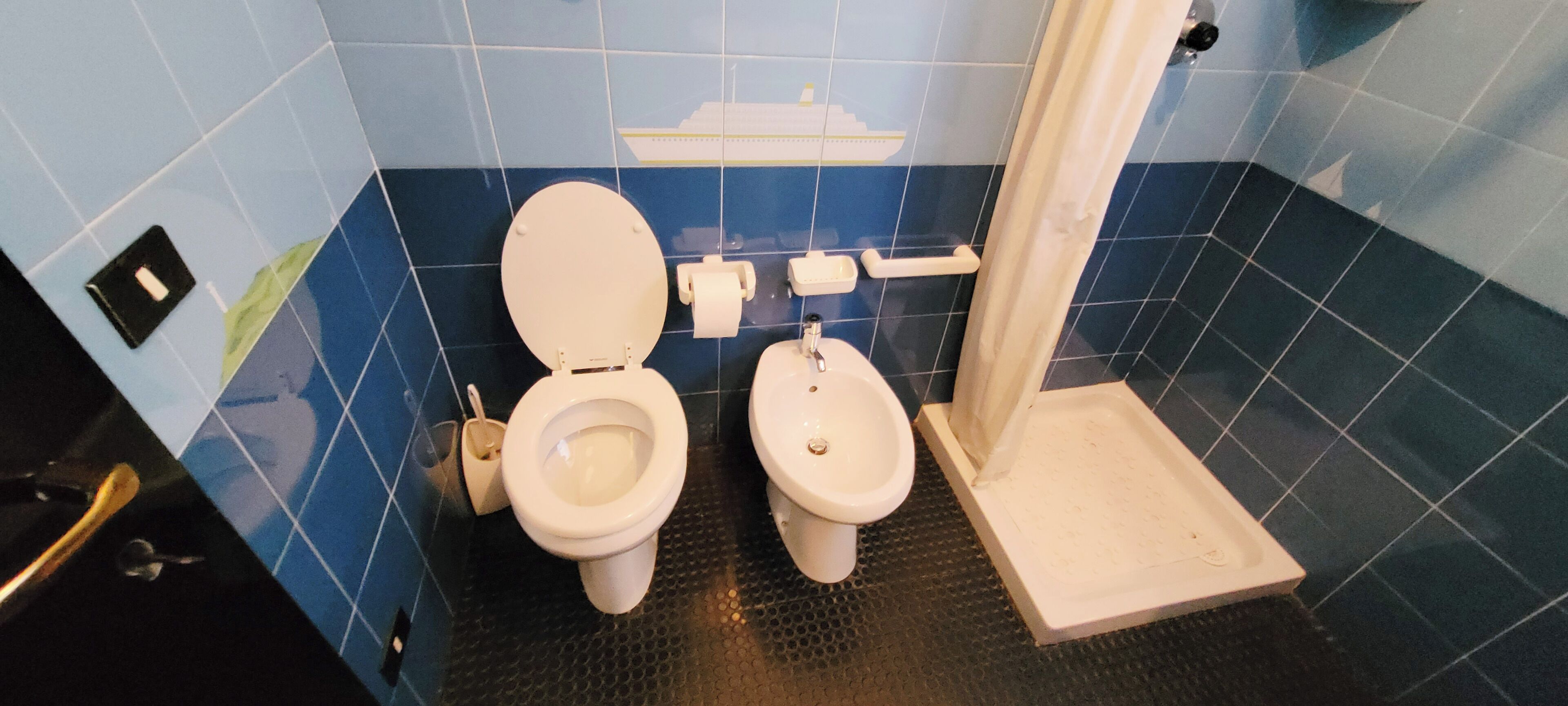 Une salle de bain avec deux toilettes, un lavabo et un espace douche.
