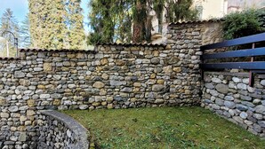 Un muro de piedra con un banco de piedra curvo y una reja de metal.