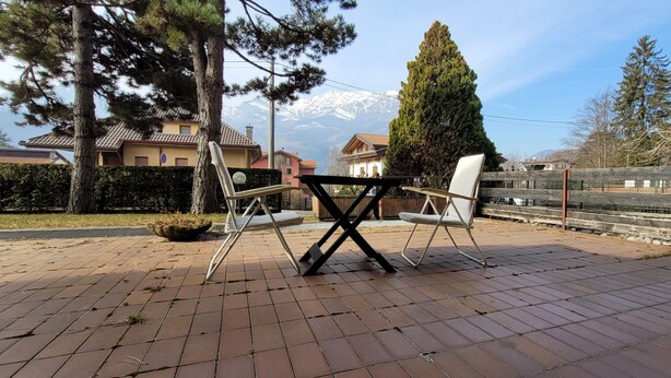 Un patio con una mesa y dos sillas, rodeado por una valla de madera y árboles.