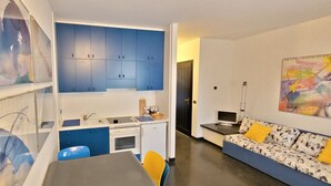Un espacio habitable compacto con kitchenette, un sofá y obras de arte en las paredes.