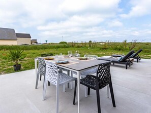 Enjoy dining al fresco with a table set for four on a patio surrounded by a grassy field and trees.