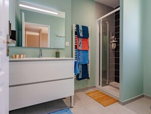 Bathroom features a sleek vanity with a mirror, sink, and glass shower enclosure.