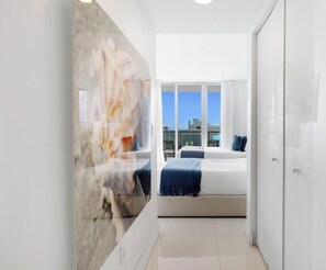 A modern hotel room with a bed, a seating area, and a view of the city skyline.