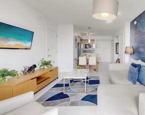 A modern living room with a sofa, a dining area, a kitchen, and a large wall map.