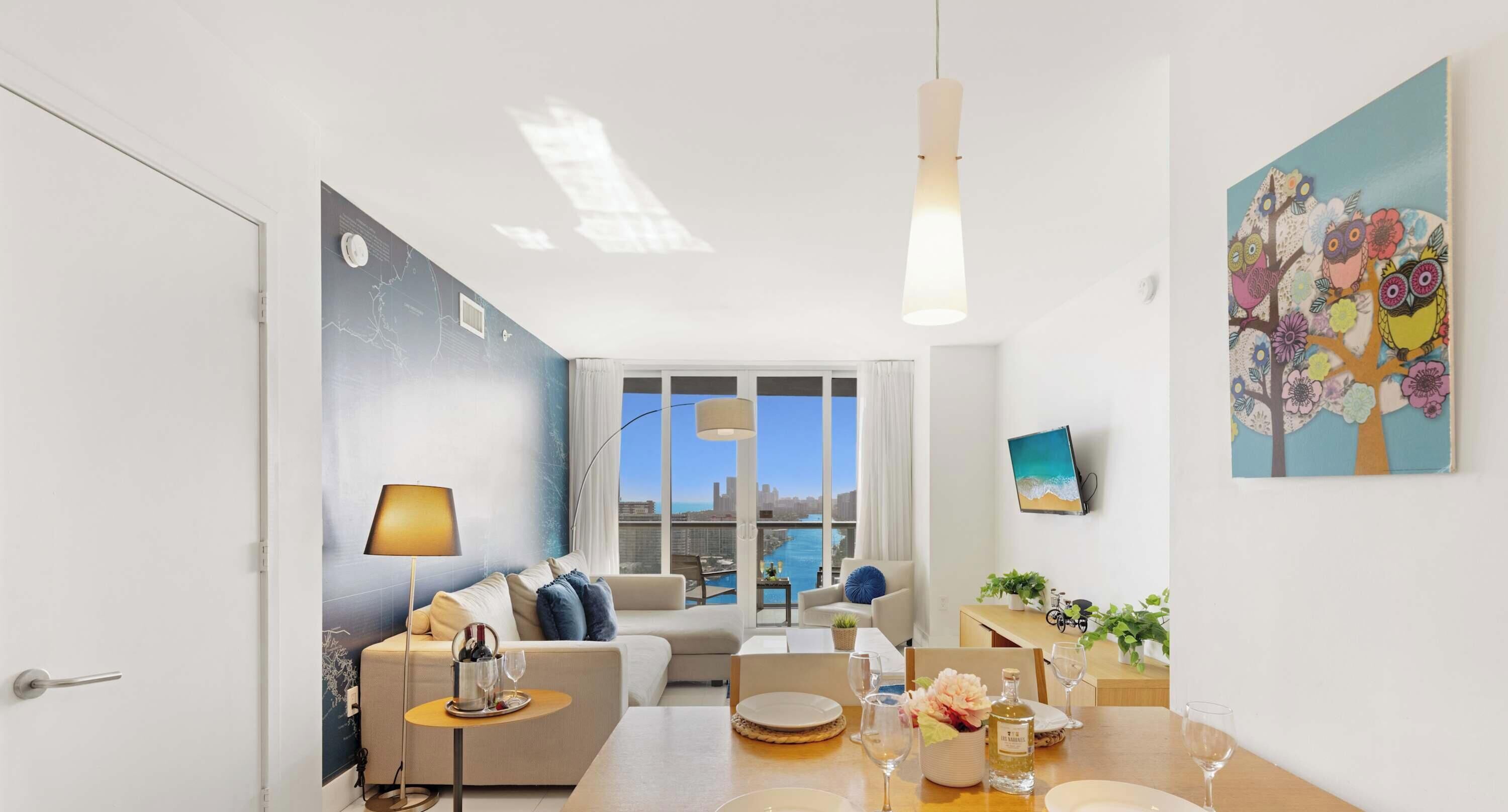 A modern living room with a sofa, dining table, and city view through large windows.