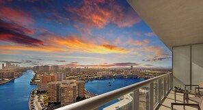 A balcony with a view of a marina, cityscape, and sunset.