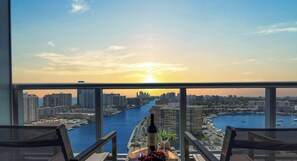 A balcony with a city view, a bottle of wine, and a fruit platter.