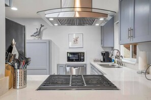 A modern kitchen with a stainless steel range hood, a microwave, a dishwasher, and a sink.