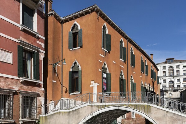 A historic building with arched windows and a bridge with metal railings.