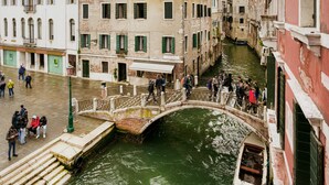 Un canal con un puente, edificios históricos y una multitud de gente.