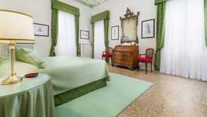 Un dormitorio con cama, cómoda, silla, lámpara y espejo.