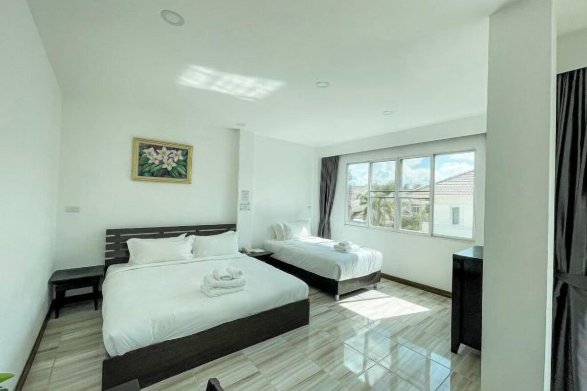 Habitación de hotel moderna con dos camas, un ventanal con cortinas, un cuadro en la pared y un escritorio pequeño.