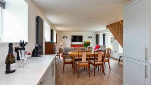 A spacious kitchen with a dining area, wooden flooring, and a staircase leading to another level. - The Warren (Stamford)
